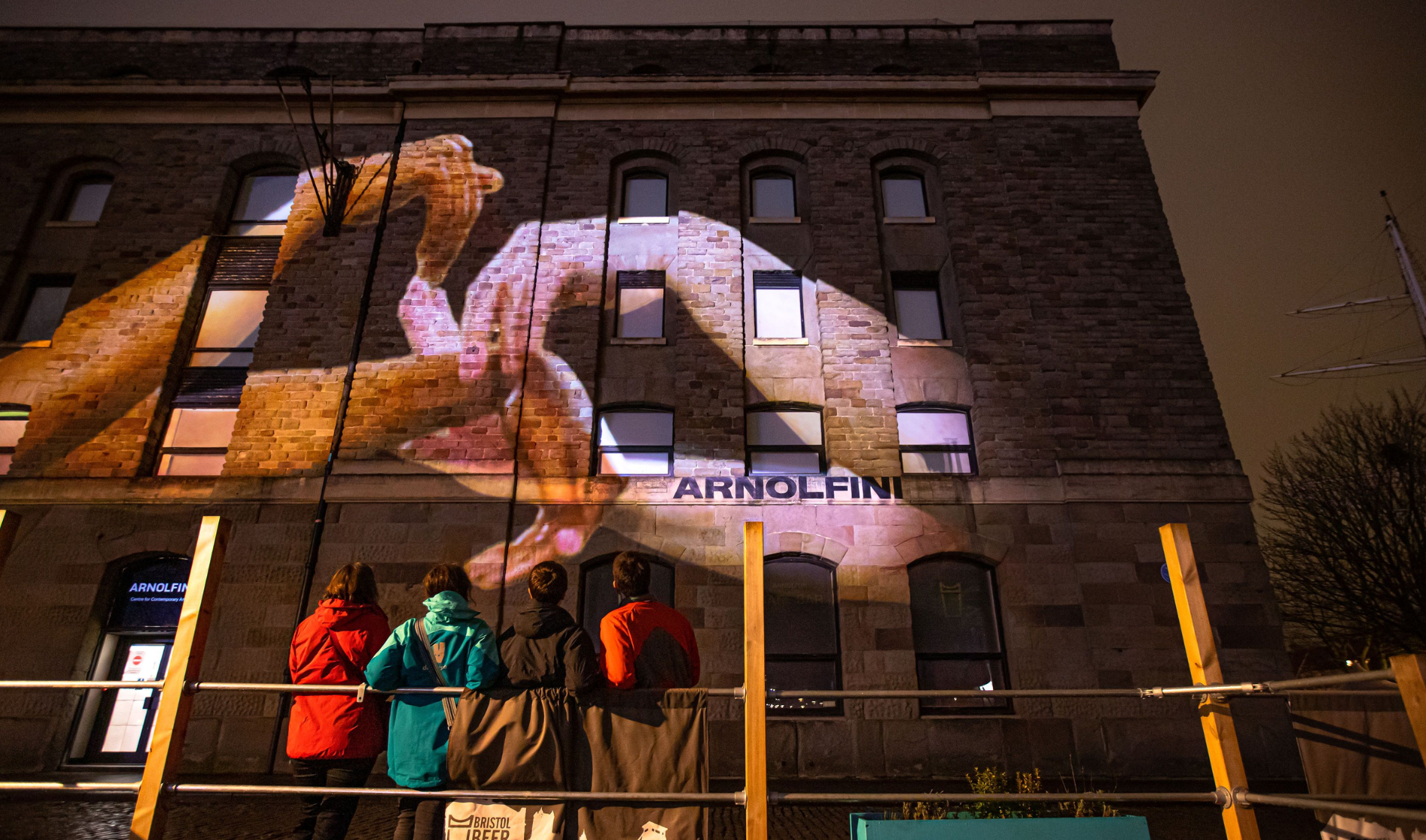 Images of hands doing BSL are projected onto a building