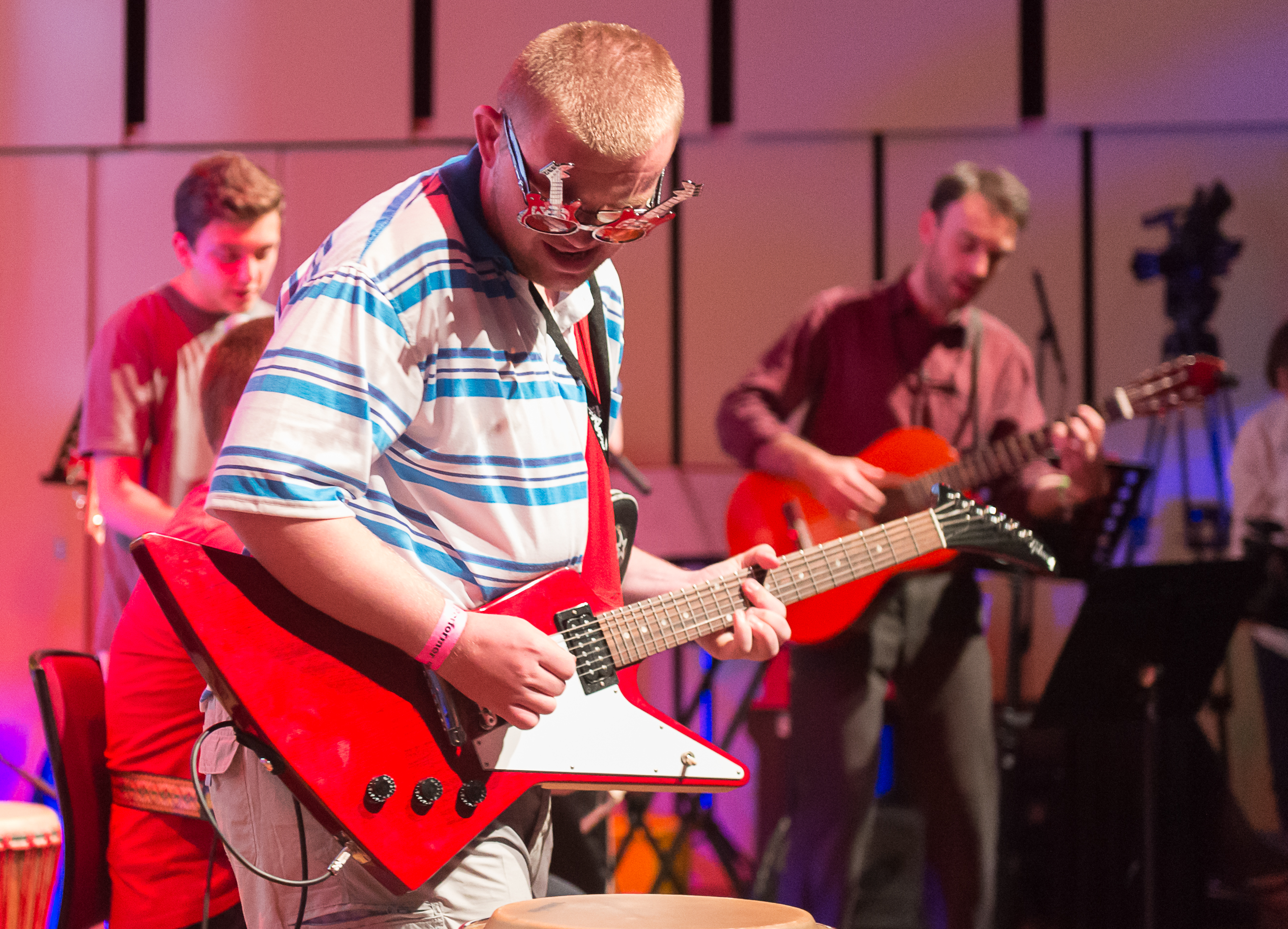 Josh playing a red electric guitar with guitar shaped glasses