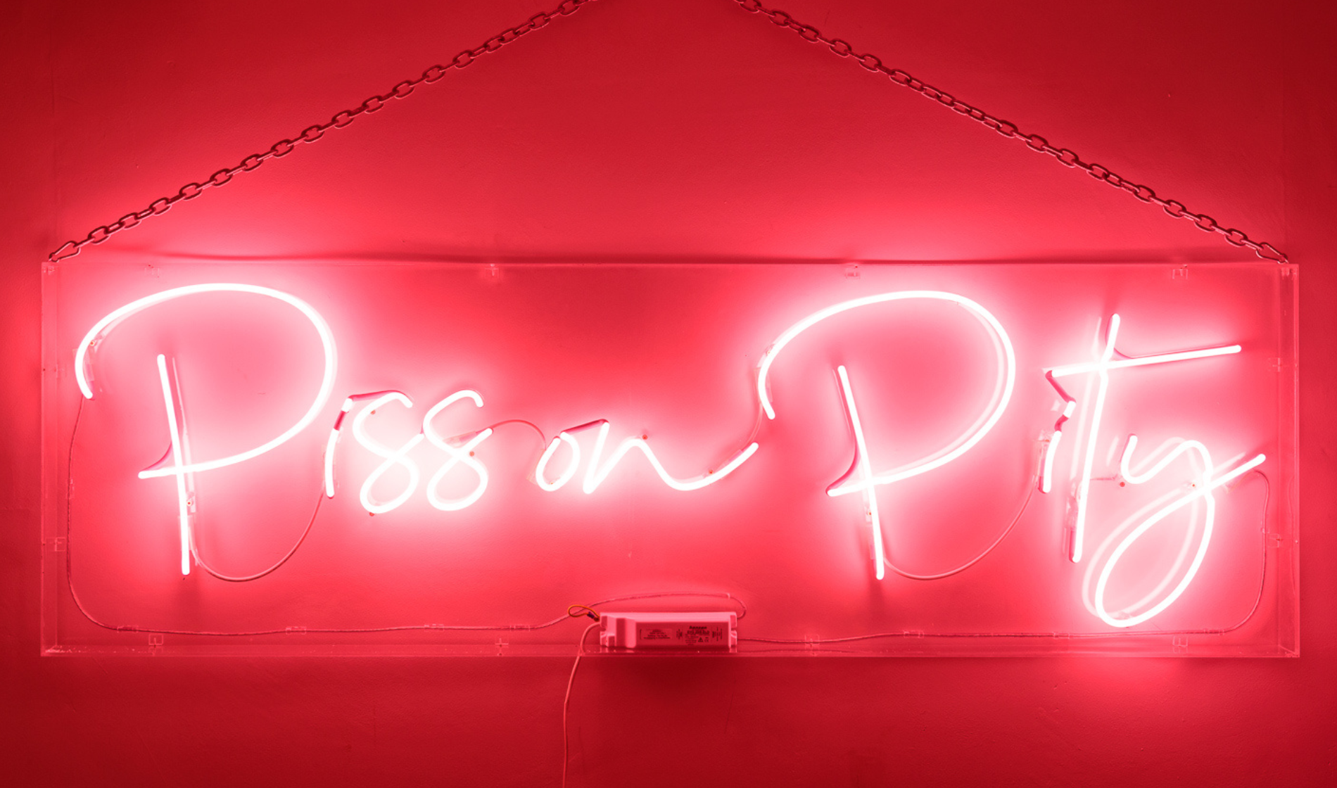 Neon sign saying 'Piss on Pity'