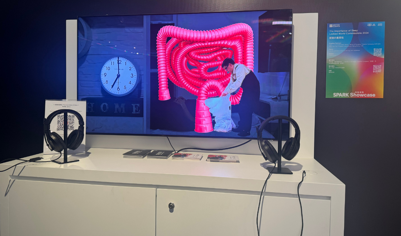 a desk holds a screen with a bright coloured display and two sets of headphones.