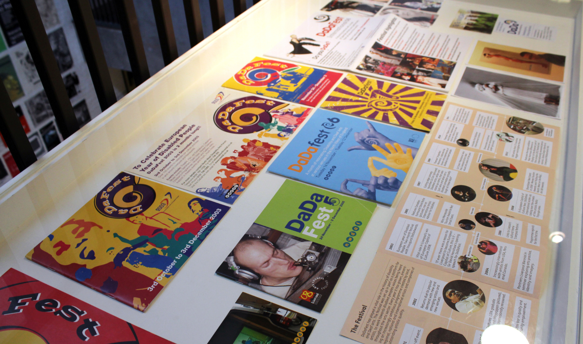 A table top is covered in past leaflets and programmes from DaDaFest Events gone by