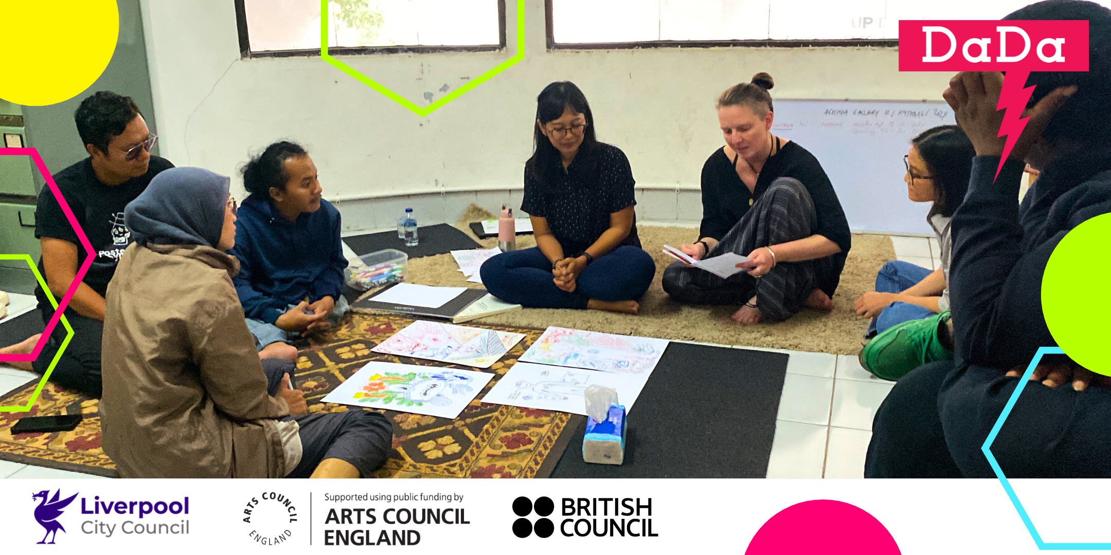 A group of disabled artists and practitioners are sat on the floor in a circle with pieces of paper in the centre.